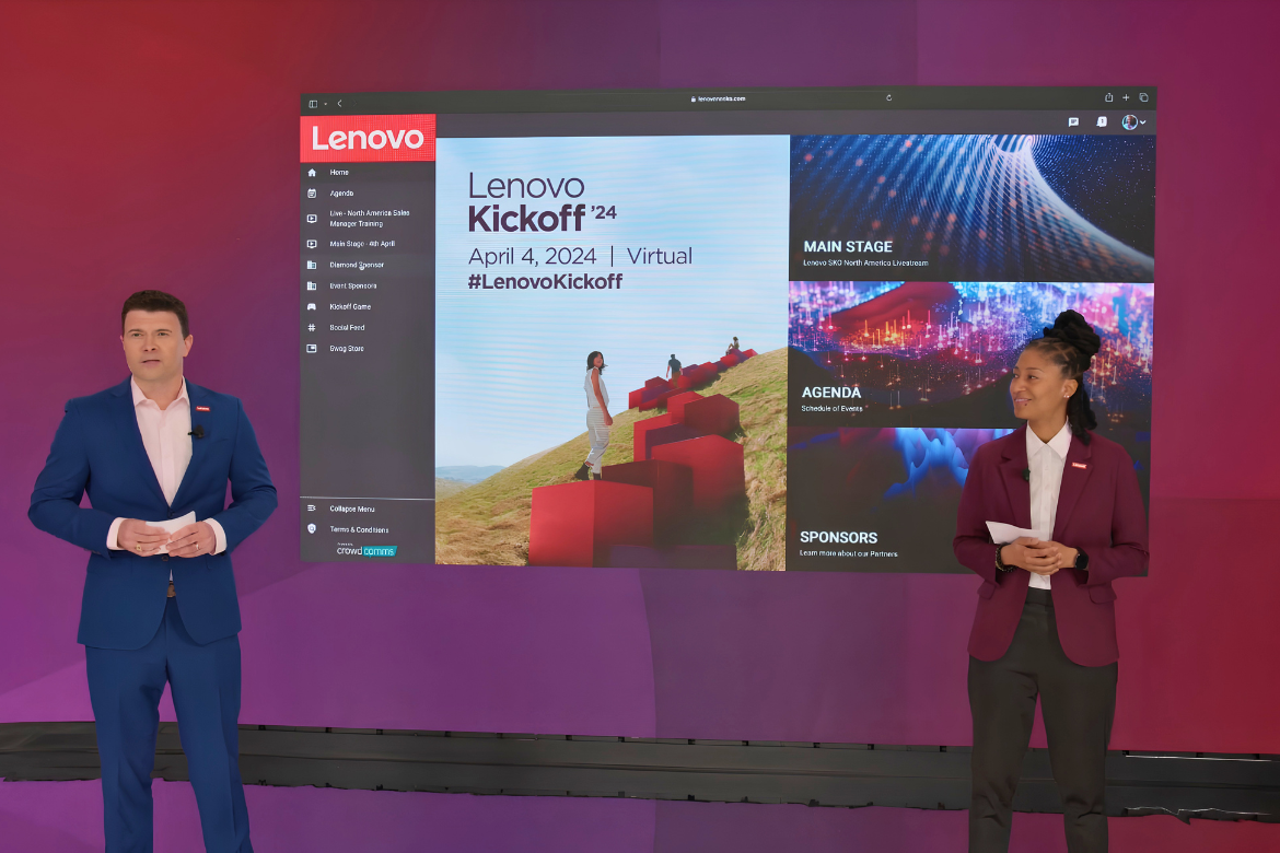 Two hosts standing on the broadcast studio floor against a LED video wall backdrop, presenting the Lenovo Kickoff '24 virtual event platform displayed on a large screen behind them, showing the event's homepage with navigation menu, event branding for "Lenovo Kickoff '24 — April 4, 2024 | Virtual | #LenovoKickoff," and tiles for Main Stage, Agenda, and Sponsors.