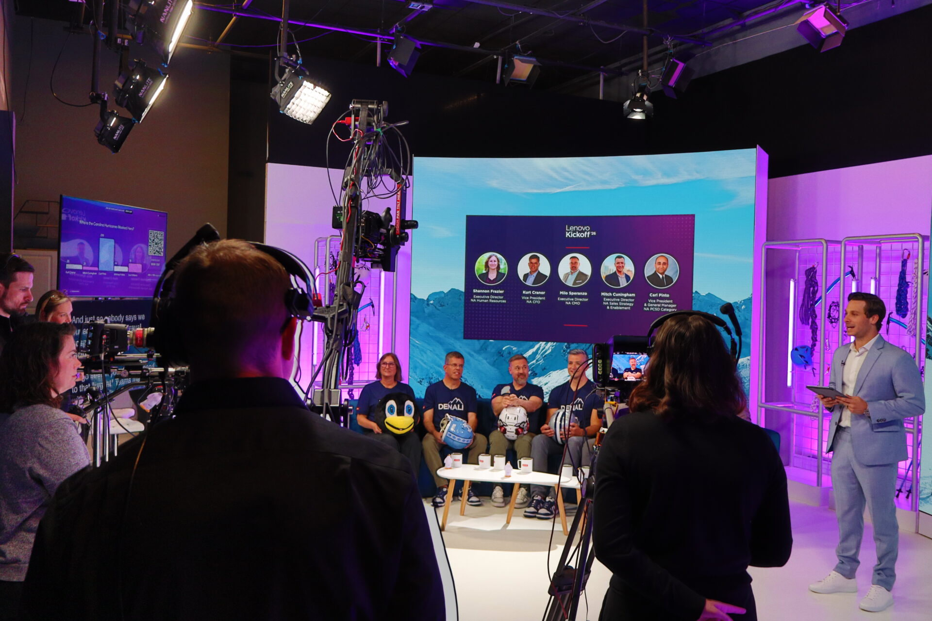 A behind-the-scenes view of the TSEC Studios broadcast floor during a live Lenovo Kickoff '26 segment, with a panel of masked participants seated on set, a host presenting, and the production crew visible in the foreground.