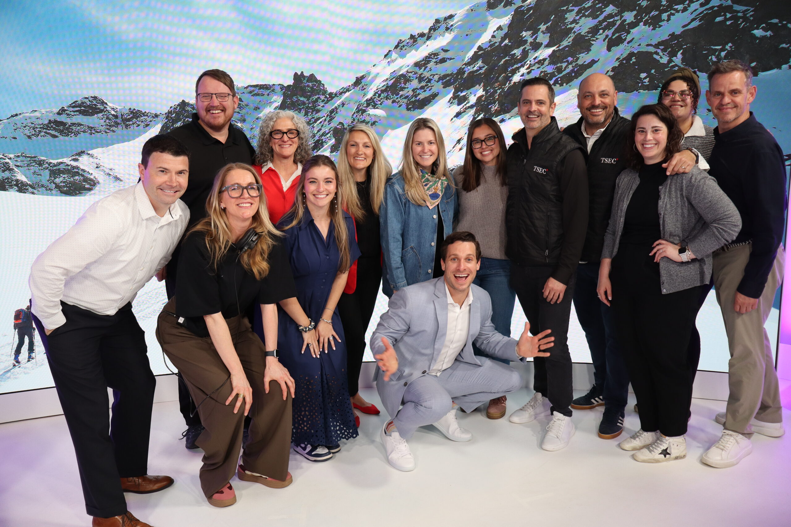 The TSEC event production team poses together on the broadcast studio set in front of a large LED screen displaying a mountain landscape after the Lenovo North America Sales Kickoff 2026.